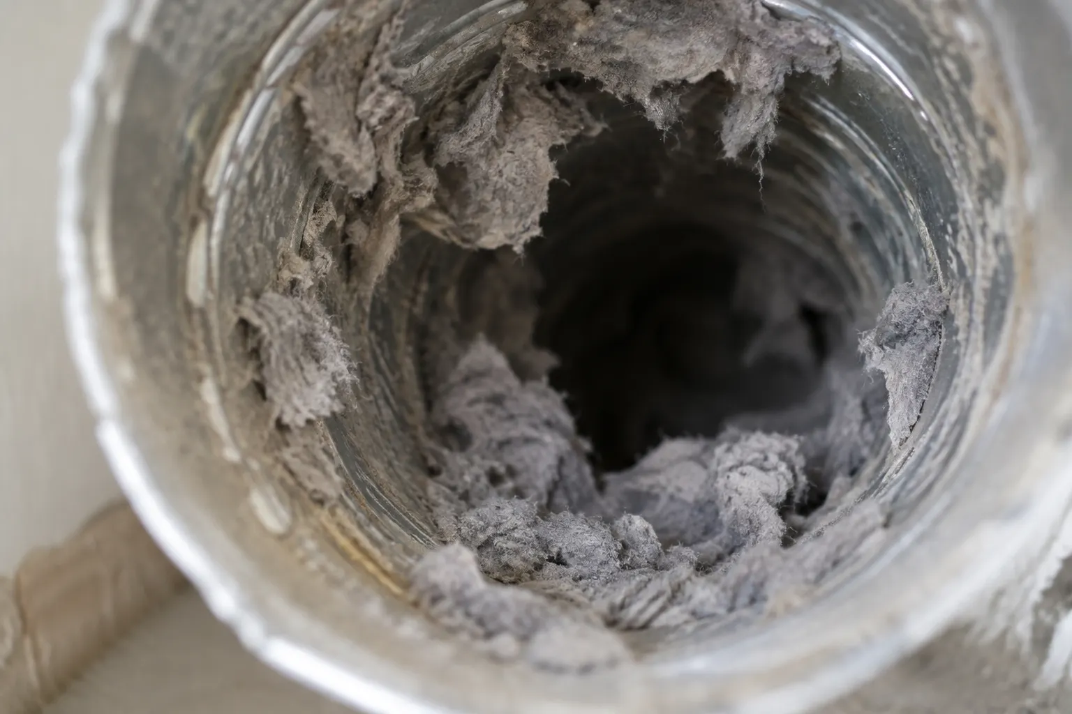 Close-up of lint buildup near a dryer exhaust vent
